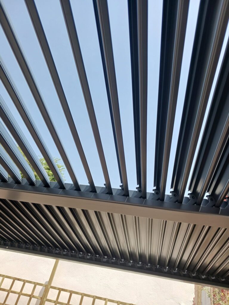 pergola-bioclimatica-lamas-orientables Detalle inferior de una pérgola bioclimática metálica con lamas orientables en color gris oscuro