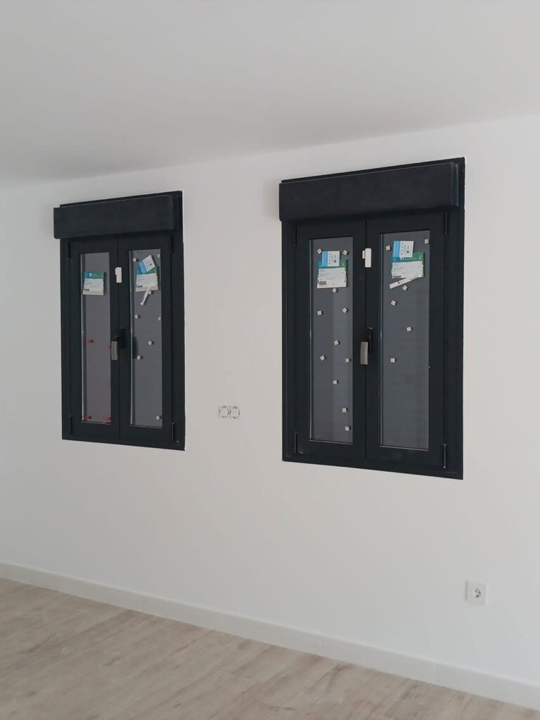 ventanas-aluminio-negras-persianas-integradas Dos ventanas de aluminio negro con persianas enrollables integradas en una estancia